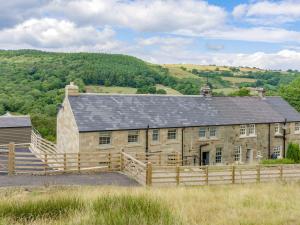 an old stone barn with a fence in front of it at Ivy Cottage in Beck Hole