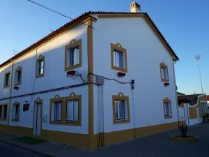 een wit gebouw met ramen aan een straat bij Casa da Alagoinha in Vila Nova de Milfontes