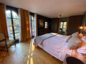 a bedroom with a bed and a chair and windows at L'enchantement Vacation home by Rendez-Vous Mont-Tremblant in Mont-Tremblant