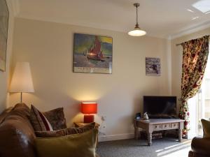 sala de estar con sofá y TV en Cosy Cotswolds Townhouse, en Honington