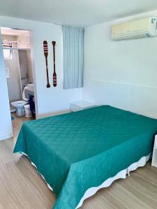 1 dormitorio con cama verde y baño en FLAT MANIHI - MURO ALTO, en Porto de Galinhas