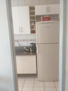 a kitchen with white cabinets and a white refrigerator at Apartamento perto da praia de Itaparica in Vila Velha