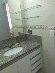 een badkamerbar met een wastafel en een spiegel bij Apartamento perto da praia de Itaparica in Vila Velha