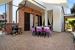 un patio con tavolo, sedie e griglia di Villa La palmetta a Peschiera Borromeo