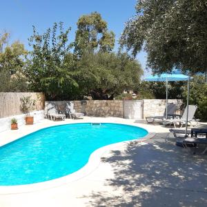 uma piscina num quintal com cadeiras e um guarda-sol em Villa Chariklia Studios em Kambiá