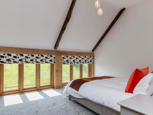 a bedroom with a bed and large windows at East Dunster Deer Farm Linny in Cadeleigh