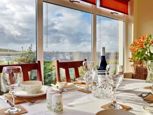 tavolo con bicchieri da vino e vista sull'acqua di Padraigs Cottage a Howmore