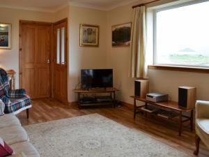 a living room with a couch and a television at Padraigs Cottage in Howmore