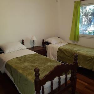 1 dormitorio con 2 camas y una ventana con cortinas verdes en CasasierraMDQ Lugar de encanto para descansar en Sierra de los Padres