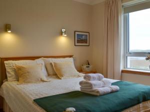 a bedroom with a bed with towels on it at Padraigs Cottage in Howmore