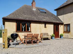 a house with a patio with chairs and a grill at The Lodge At Elmley Meadow in Little Comberton