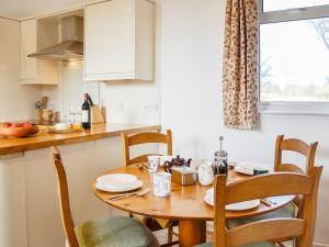 una pequeña cocina con mesa de madera y sillas en The Coach House, en Alford