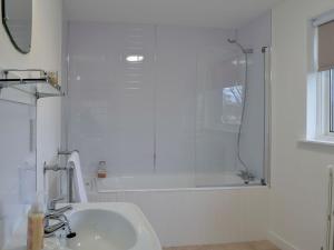 a white bathroom with a shower and a sink at The Coach House in Alford