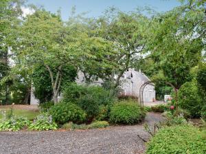 a garden with a greenhouse and some bushes and trees at The Coach House in Alford