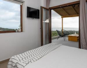 a bedroom with a bed and a balcony with a television at Hilltop Resort at Kefalonia in Angón