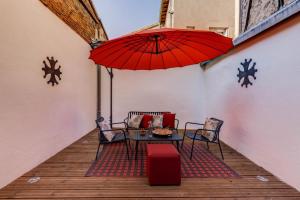 eine Terrasse mit einem Tisch und einem roten Regenschirm in der Unterkunft Espaces 55, Maison de ville au centre de Lavaur in Lavaur