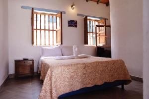 a bedroom with a bed and two windows at Hotel Villa Paz in Villa de Leyva