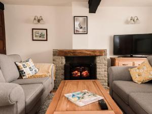 a living room with two couches and a fireplace at Three Batch Cottages in Chaddesley Corbett