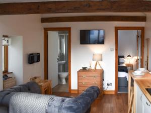 ein Wohnzimmer mit einem Sofa und einem TV an der Wand in der Unterkunft Pear Tree Barn in Crooklands