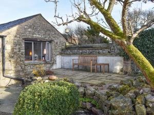 a stone house with a bench and a window at Pear Tree Barn in Crooklands