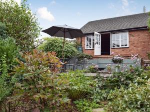 a house with an umbrella in the garden at Three Batch Cottages in Chaddesley Corbett