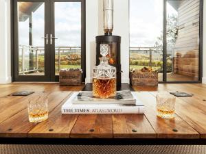 a bottle of whiskey on a wooden table with two glasses at Strathspey Lodge in Duthil