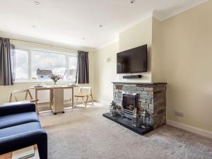 a living room with a fireplace and a tv at Church View in Probus