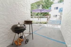 a bbq grill and an umbrella on a patio at Casa con PISCINA PRIVADA a 4 min del IRTRA REU in Ajaxá