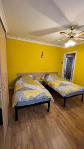 two beds in a room with yellow walls at Palaz 6 - 2 bedroom flat in Edmonton