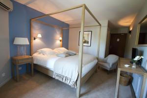 a bedroom with a canopy bed and a chair at Hotel Santa Maria in Saint-Florent