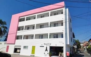 ein weißes und rosafarbenes Gebäude mit einer Person, die davor steht in der Unterkunft Azul departamento 34 m2 Nuevo in Jiutepec