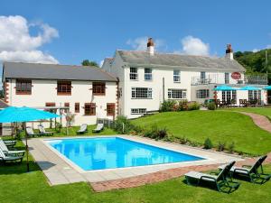 a large house with a swimming pool in the yard at The Hay Barn in Sidbury