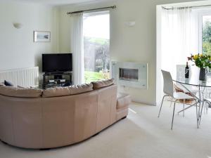 a living room with a brown couch and a table at Moonrakers in Ruan Lanihorne