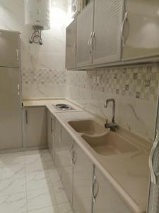 a white kitchen with a sink and a stove at Three Rose in AlUla +52 photos