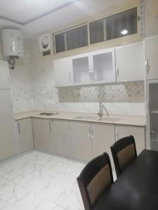 a kitchen with white cabinets and a table and chairs at Three Rose in AlUla