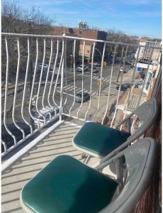 2 stoelen op een balkon met uitzicht op een parkeerplaats bij Double-Mirrored Glass Room in Queens in Corona