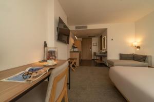 ケレタロにあるStadía Suites Querétaro Centro Históricoのベッドとデスクが備わるホテルルームです。