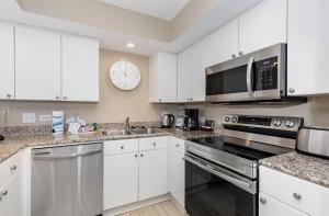 默特尔比奇New to rentals and newly re-decorated - 605 Brighton Kingston Plantation condo的厨房里有白色的橱柜，墙上挂着一个钟