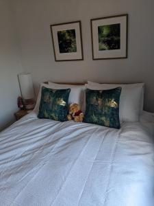 a teddy bear sitting on a bed with two pillows at Former Romsey Brewery House in Romsey