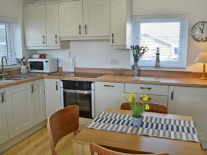 ビードネルにあるDunstanburgh Viewの白いキャビネットと花のテーブル付きのキッチンが備わります。