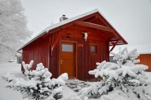 a red cabin with snow covered trees in front of it at Holiday home at Aquapark Tatralandia in Liptovský Mikuláš