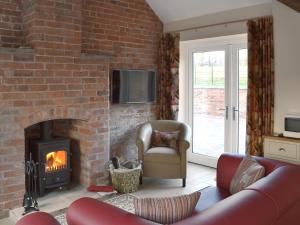 a living room with a brick wall and a fireplace at Betley Court Farm 2 in Betley