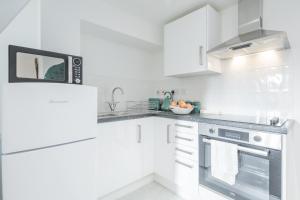 a white kitchen with a stove and a microwave at Cosy Two bed Apartment for family and contractors Milton Keynes by O&J Real Estate in Milton Keynes