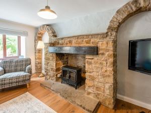 a living room with a stone fireplace and a television at The Barn House in Hawes