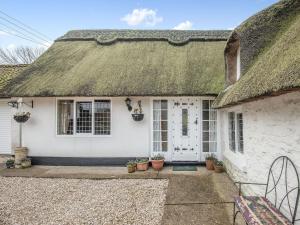 a white cottage with a thatched roof with potted plants at The Thatch in South Willingham