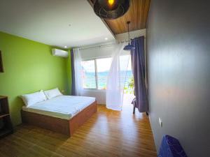een slaapkamer met een bed en een groot raam bij Lovely Beach House in Anilao in Mabini