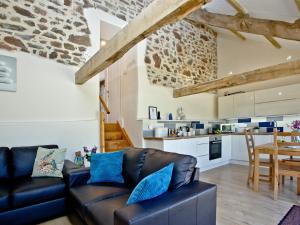a living room with a leather couch and a kitchen at Bluetit Cottage in Kings Nympton