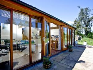 a house with large glass windows and a patio at Bluetit Cottage in Kings Nympton