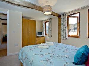 sypialnia z niebieskim łóżkiem z niebieską kołdrą w obiekcie Bluetit Cottage w mieście Kings Nympton