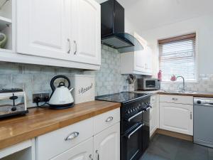 a kitchen with white cabinets and a stove top oven at Horseshoe House - Ukc2743 in Watton